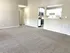 Bright and inviting living space with plush carpeting and a sleek, modern kitchen with stainless steel appliances.