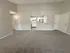 Inviting open-concept living space with plush carpeted floors, neutral walls, and a modern kitchen view.