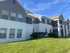 Charming apartment building with stylish two-tone facade, expansive windows, and lush green lawn under a bright blue sky.