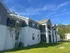 Charming two-story apartment building with modern architecture, featuring elegant balconies and surrounded by lush greenery under a vibrant blue sky.