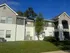 Inviting modern apartment building with spacious balconies, surrounded by lush greenery and a bright blue sky.