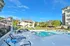 Inviting outdoor pool area surrounded by lush greenery and modern apartment buildings under a bright blue sky.