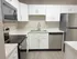 Modern kitchen with sleek stainless steel appliances, elegant marble countertops, and ample white cabinetry for stylish storage.