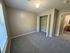Inviting bedroom space with plush carpet, ample closet storage, and natural light from large windows.