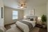 Inviting bedroom with elegant decor, cozy bed with plush pillows, stylish ceiling fan, and serene natural light.