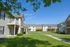 Charming apartment complex with sunny balconies, lush green lawns, and inviting communal spaces under a clear blue sky.