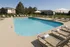 Inviting outdoor pool with elegant loungers and umbrellas, surrounded by lush greenery and stylish apartments.