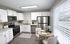 Modern kitchen with sleek stainless steel appliances, white cabinets, and a cozy dining area with large window.