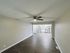 Bright, spacious living area with modern ceiling fan, leading to a sleek kitchen with stainless steel appliances.
