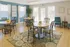 Bright and welcoming seating area with elegant wooden tables, stylish chairs, vibrant artwork, and natural light streaming through large windows.