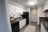 Chic modern kitchen with sleek black appliances, white cabinets, and elegant wood flooring, offering a sophisticated and practical culinary space.
