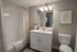 Elegant modern bathroom featuring a white vanity with a sleek mirror, soft lighting, and a cozy bathtub with a stylish tile backdrop.