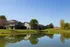Charming residential community with modern houses overlooking a serene pond and lush greenery, perfect for tranquil living.