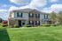 Charming two-story brick and siding apartment building with vibrant landscaping and spacious front lawn, perfect for serene living.