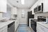 Modern kitchen with sleek appliances, white cabinetry, and a stylish coastal painting adding a fresh touch.