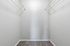 Spacious walk-in closet with sleek white shelves and plush carpeting, perfect for a luxurious storage solution.