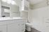 Elegant bathroom with large mirror, modern vanity, and pristine bathtub, showcasing minimalist design.