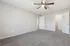 Bright, spacious bedroom with plush carpeting, a stylish ceiling fan, and ample natural light. Features dual doors for easy access and a neutral color palette for a welcoming atmosphere.