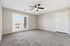 Bright and spacious living room with plush carpeting, ceiling fan, and large French doors leading to a balcony.