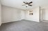 Inviting living room with plush carpeting, modern ceiling fan, and cozy open-plan design leading to a sleek kitchen.