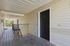 Inviting apartment entrance with a sleek black door, nestled in a charming open-air corridor with natural light and greenery.