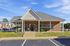 Charming brick apartment complex with a welcoming entrance, surrounded by manicured landscaping and ample parking space.