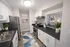 Elegant modern kitchen with sleek countertops, white cabinetry, and stainless steel appliances. Bright atmosphere complemented by stylish decor and vibrant plants.