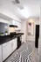 Modern kitchen with sleek black countertops, white cabinetry, and stylish geometric decor, enhanced by artistic wall art and warm lighting.