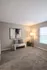 Elegant living space with plush carpeting, modern artwork, and cozy seating illuminated by a chic floor lamp.