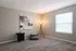 Bright and elegant room featuring modern d&eacute;cor with a sleek floor lamp, abstract wall art, and a cozy pouf under natural light from a large window.