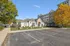 Inviting apartment complex with charming clubhouse, surrounded by lush greenery and vibrant autumn trees, offering ample parking space and a modern exterior design.