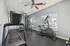 Bright and inviting fitness room with state-of-the-art gym equipment, ceiling fans, and natural light streaming through large windows.