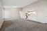Spacious living area with plush carpeting, natural light, and modern kitchen with white cabinetry and stainless steel appliances.
