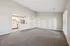Bright and open living space with plush carpet, adjacent to a modern kitchen with stainless steel appliances and white cabinetry.