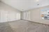 Bright and spacious living room with plush carpet, large windows, and charming French doors opening to a balcony.