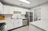 Modern kitchen featuring sleek white cabinets, stainless steel appliances, and an adjacent laundry room with washer and dryer.