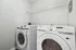Contemporary laundry room featuring sleek white Samsung washer and dryer with wall-mounted storage shelf.