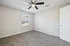 Bright and inviting empty bedroom with plush carpeting, modern ceiling fan, and large window overlooking the street.