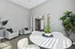 Elegant living room with modern white chairs, a sleek round table adorned with a stylish succulent centerpiece, and vibrant greenery against a soft gray backdrop.