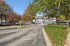 Charming apartment complex entrance surrounded by vibrant autumn foliage and well-maintained landscaping, creating a warm and welcoming atmosphere.