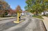 Inviting apartment complex entrance with lush autumn foliage and well-maintained grounds, offering a serene living environment.