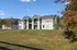 Charming duplex with a modern facade nestled in a picturesque suburban setting, surrounded by lush greenery and clear blue skies.