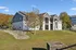 Charming two-story apartment building with spacious balconies, set amidst lush green surroundings and vibrant autumn trees, offering tranquility and modern comfort.