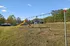 Inviting outdoor playground featuring swings and a vibrant yellow slide, set in a scenic landscape with lush green trees and a clear blue sky.