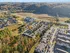 Scenic aerial view of a picturesque apartment complex surrounded by lush greenery and tranquil hills, offering a serene living experience.