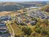 Scenic aerial view of a vibrant apartment complex nestled among lush green hills and colorful autumn trees, showcasing a serene and inviting community layout.