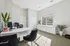 Bright and inviting office space with modern furniture, large window, and lush greenery, offering a tranquil and productive work environment.