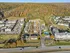 Aerial view of a charming residential community surrounded by lush autumn trees, featuring multiple apartment buildings, spacious parking lots, and a refreshing pool.