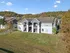 Charming apartment buildings with inviting balconies nestled in a scenic, tree-lined landscape under a bright blue sky.