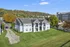 Charming residential building nestled in lush greenery with a scenic hillside backdrop, perfect for serene living.
